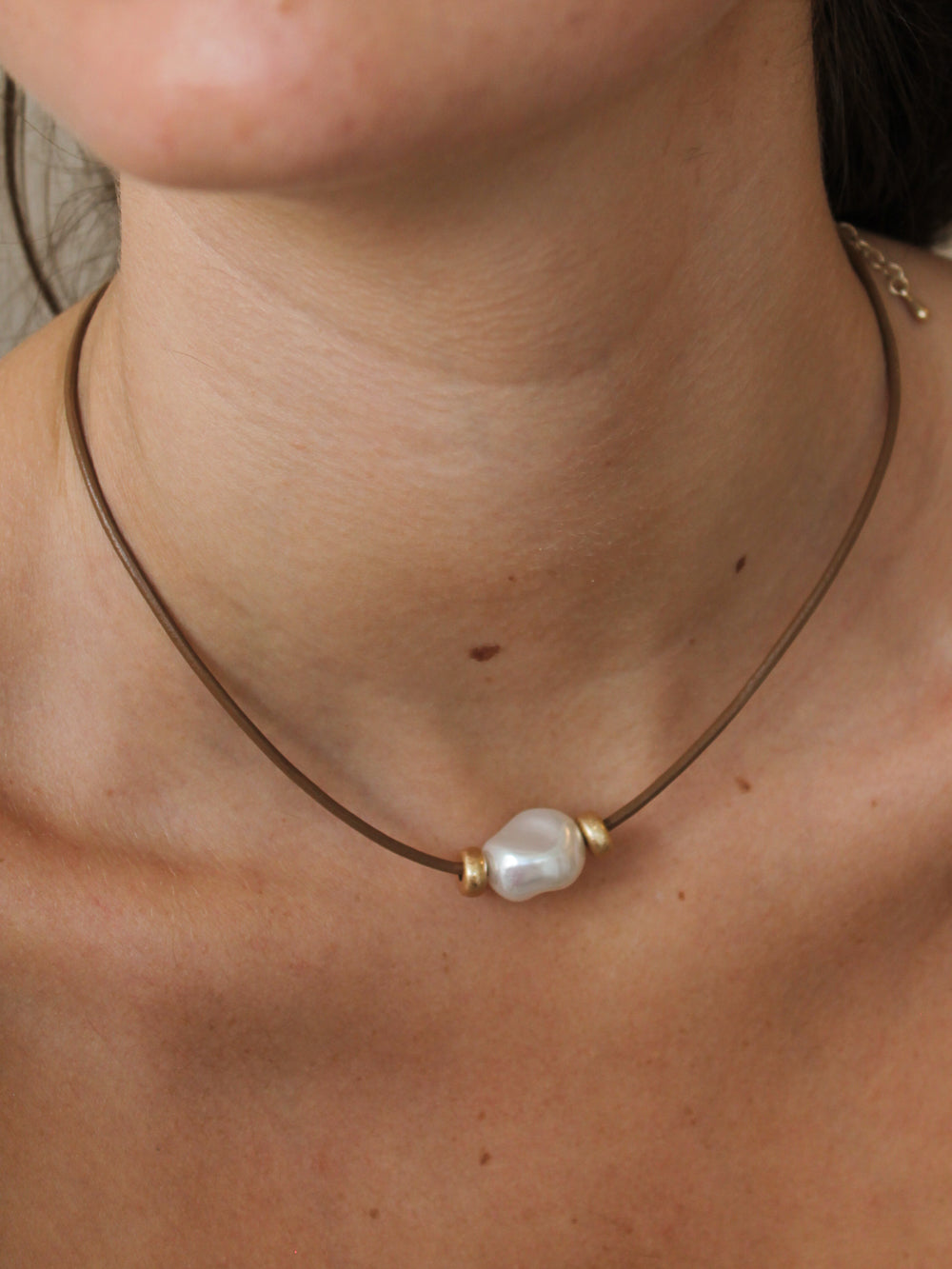 Necklace with a pearl pendant on a person's neck