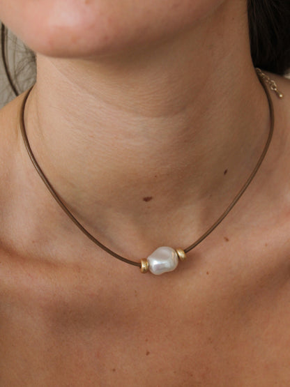 Necklace with a pearl pendant on a person's neck