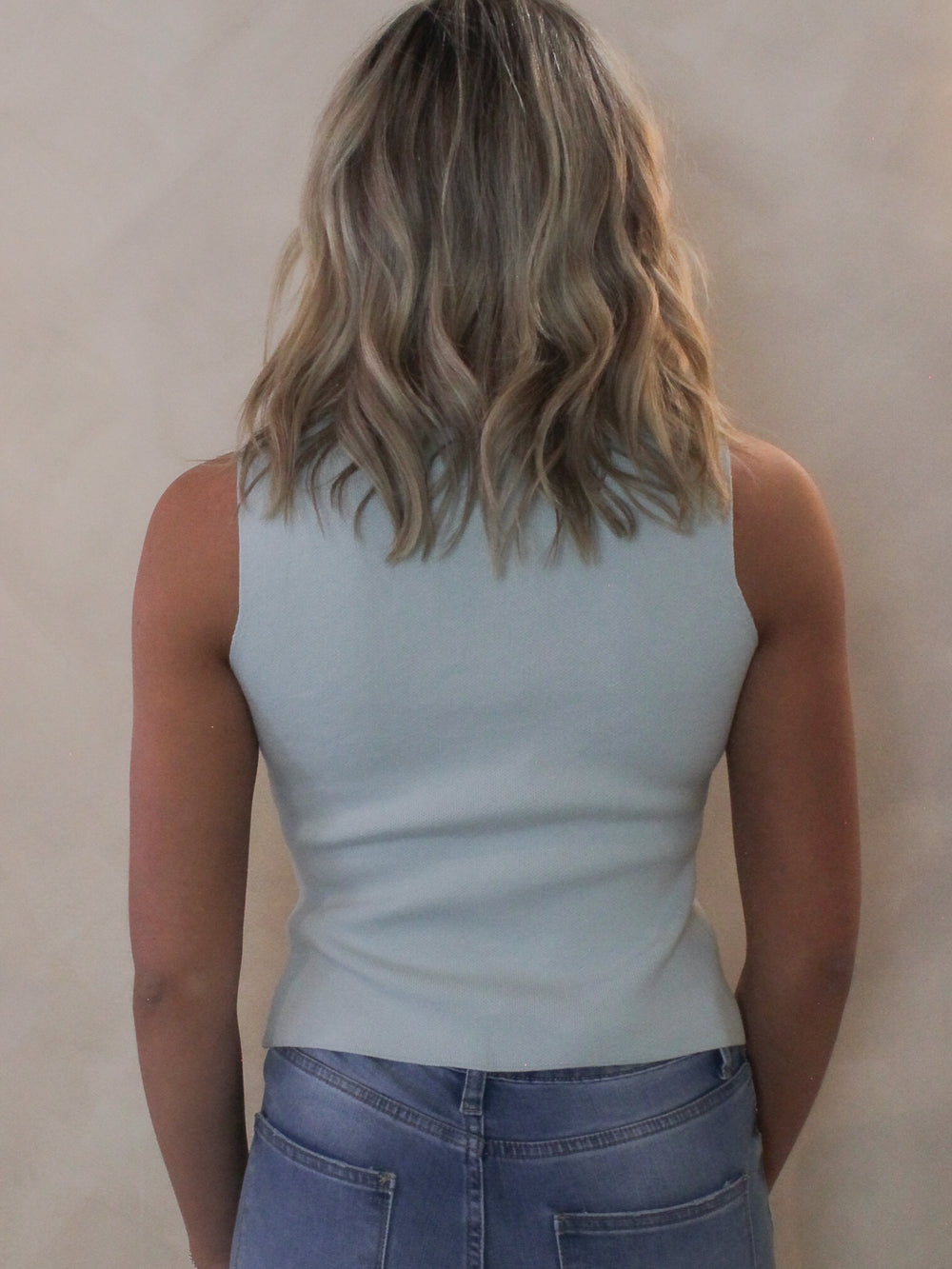 Back view of a woman wearing a light blue cardigan vest