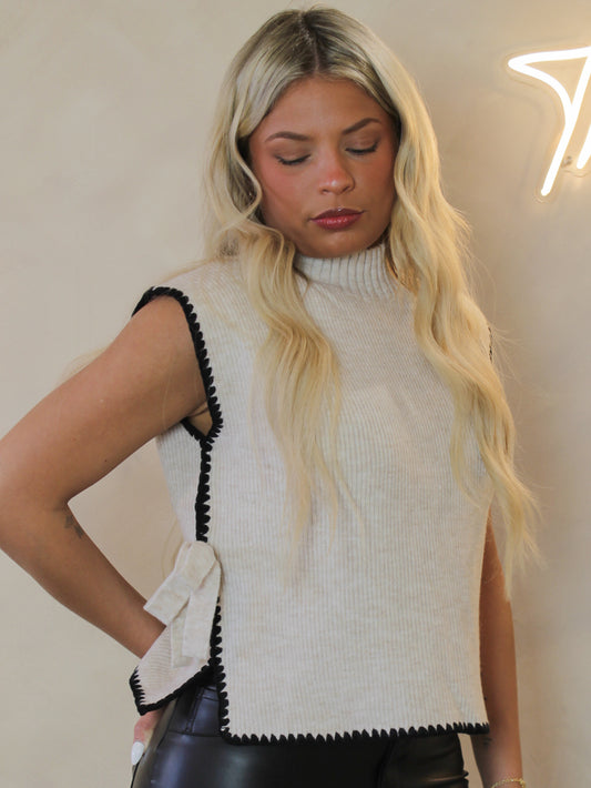 Beige sleeveless sweater with black contrast and side bow details 