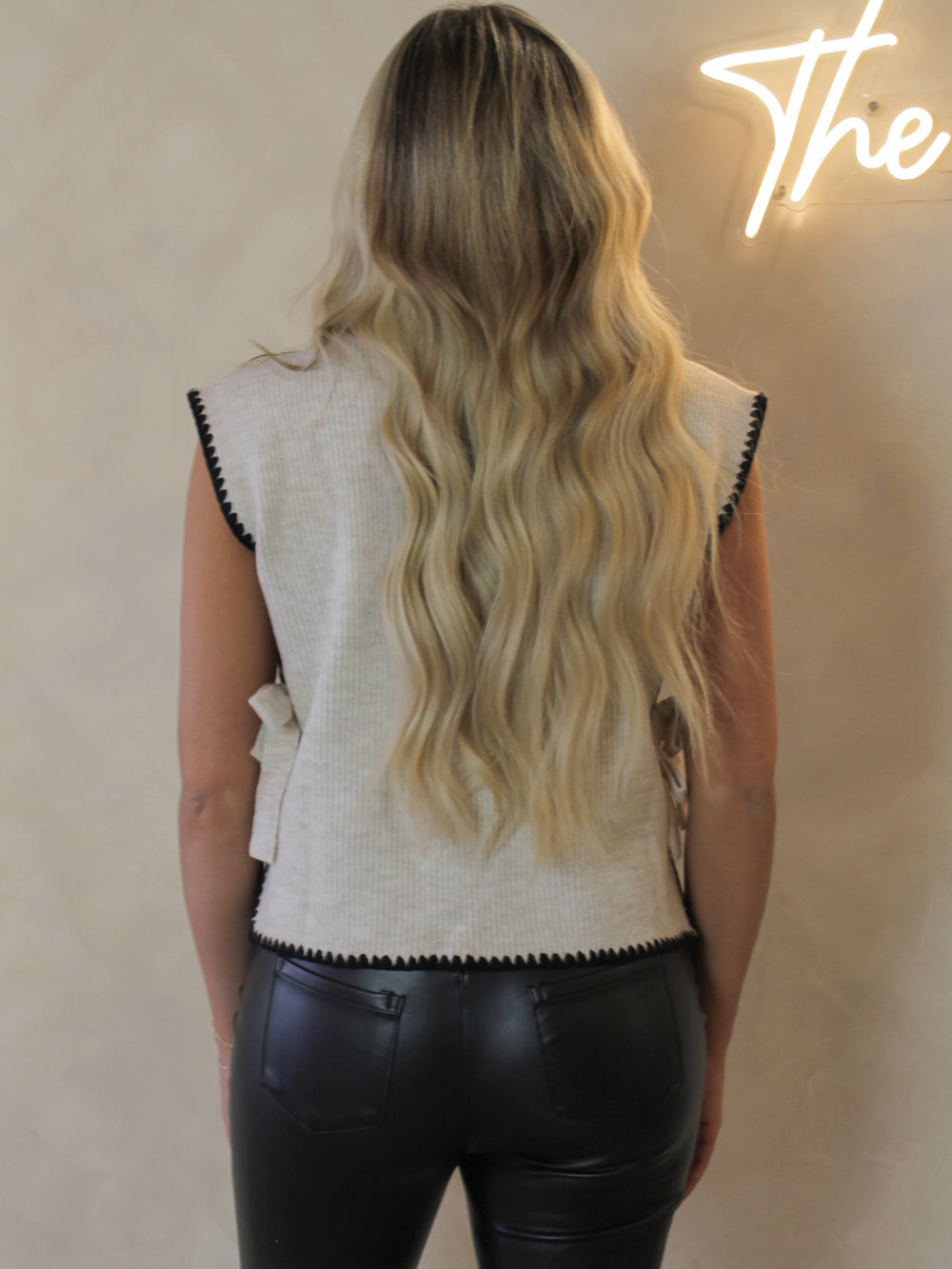 Person wearing a white sleeveless top with black trim and black pants,