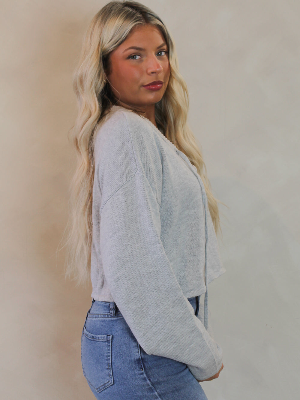 Woman wearing a cropped, grey knit sweater