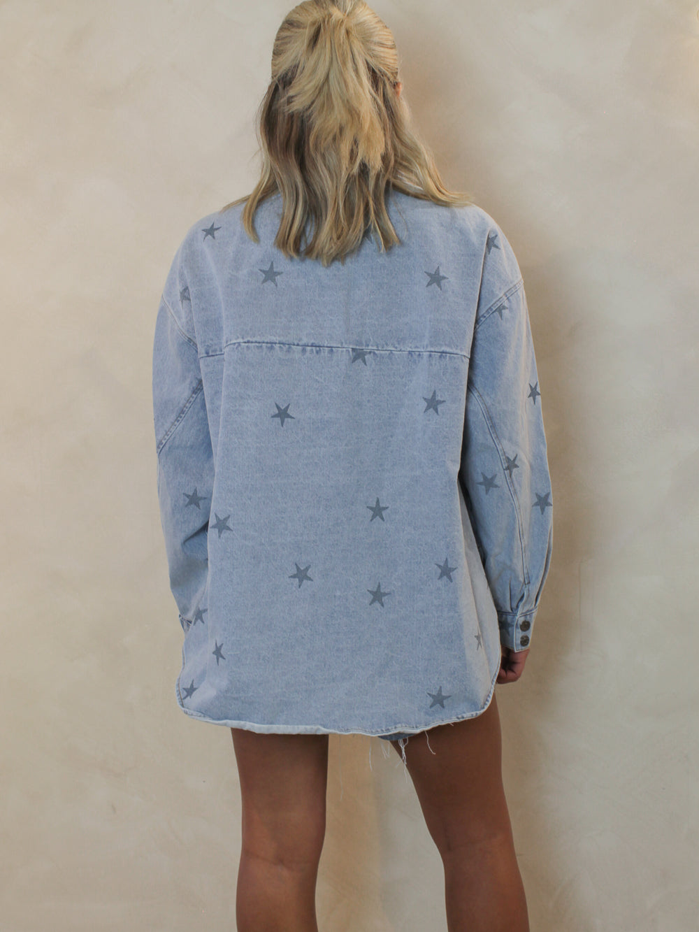 The back view of a girl wearing a long sleeve denim top with an all over star print 
