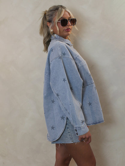 Girl wearing a blue denim, long sleeve top with an all over star print and curved hem details 