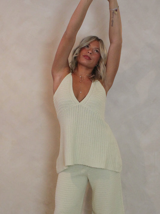 Woman wearing a light green sleeveless top and pants.