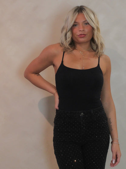 Woman wearing a black tank top and black pants with rhinestones.