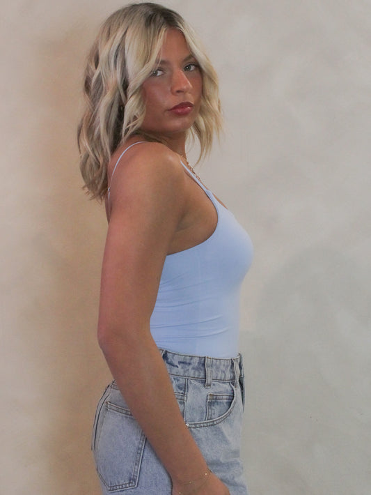 Woman wearing a cami style bodysuit with denim shorts