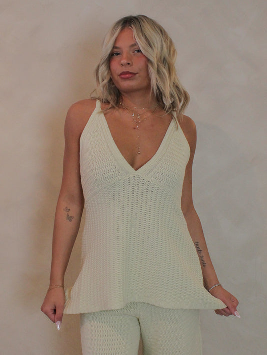 Woman wearing a light green knit sleeveless top with deep v-neckline