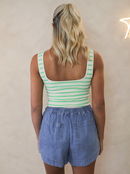 Model wearing a green and white stripe bodysuit with denim shorts