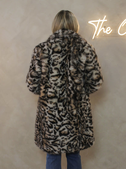 A woman viewed from behind wearing a plush faux-fur coat with an allover leopard print pattern in black, brown, and beige
