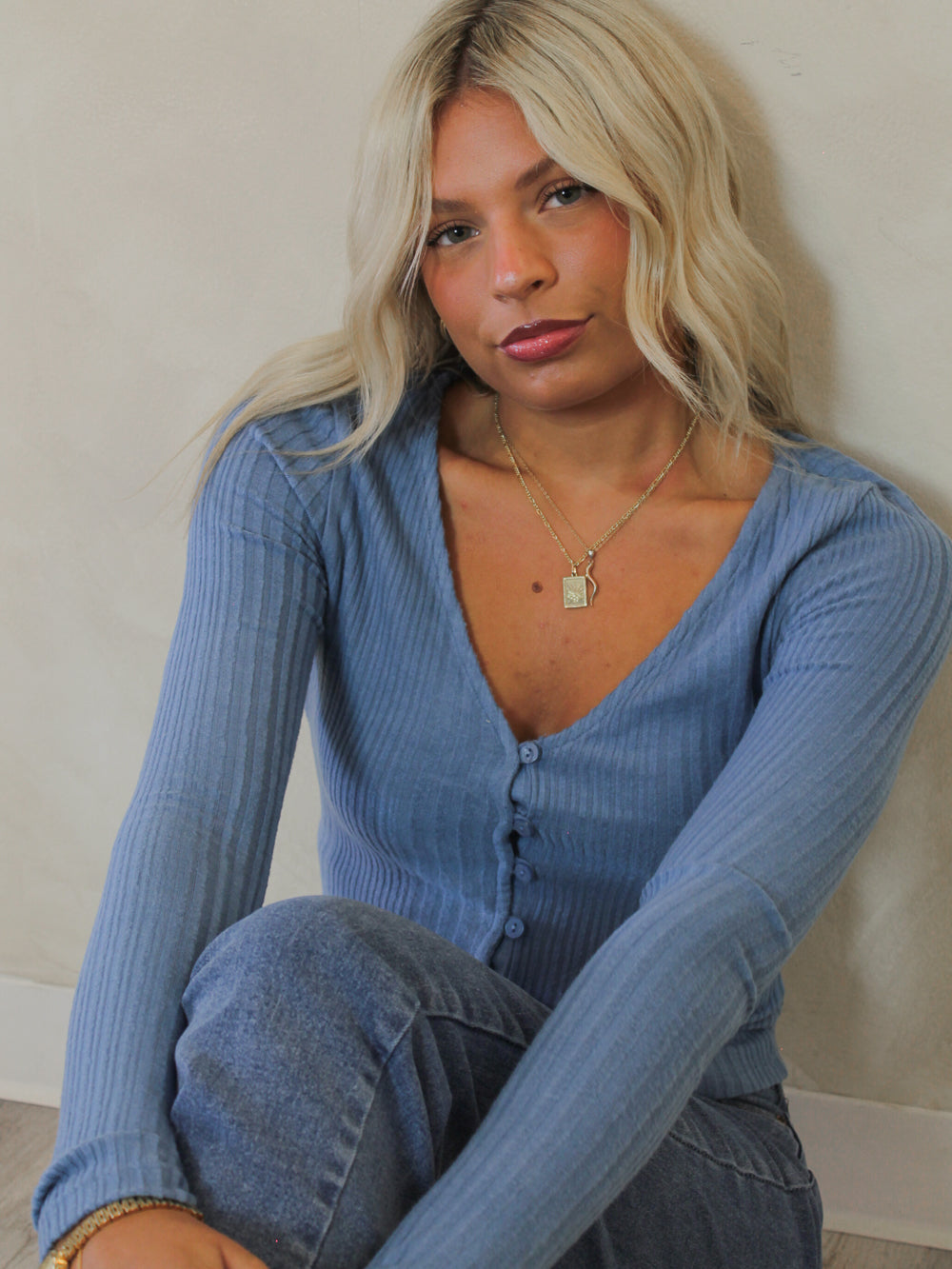 Woman wearing a blue light weight sweater with a button up detail 