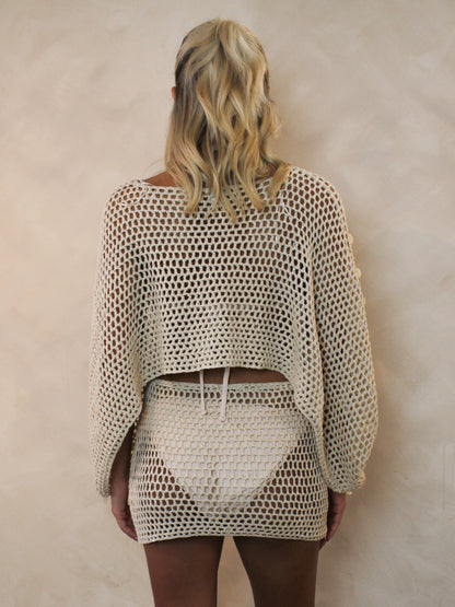 Woman wearing a beige crochet bathing suit cover up