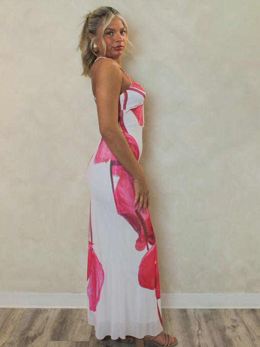 Girl wearing a fitted, white, mesh maxi dress with large floral print design paired with gold earrings for a summer vacation