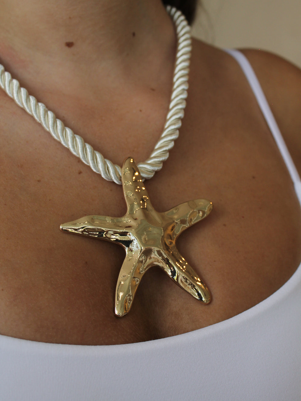 Gold starfish pendant on a white rope necklace