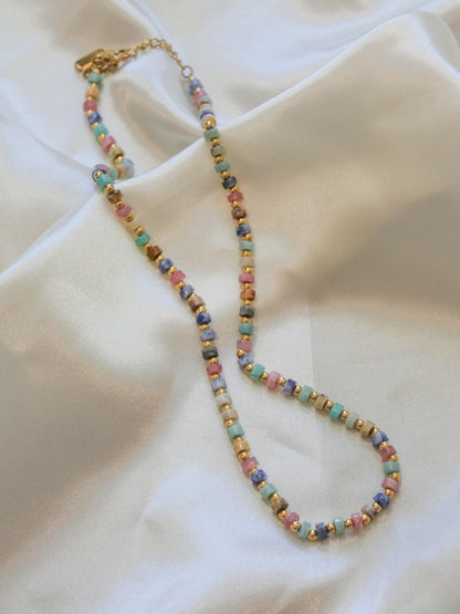 A beaded necklace with small pastel-colored round beads and gold spacer bead.
