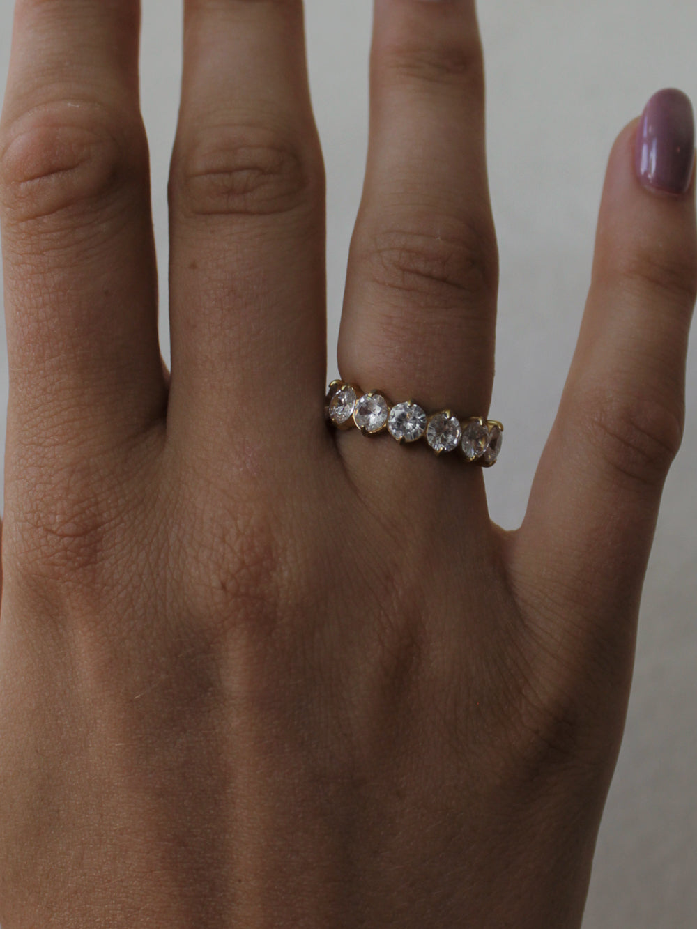a close up of a girl wearing a gold eternity band with clear, round stones