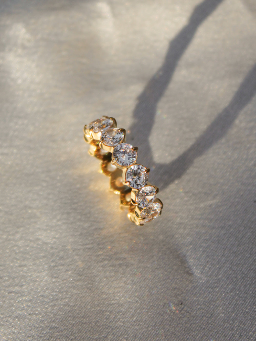 A gold ring featuring a row of clear round-cut gemstones.