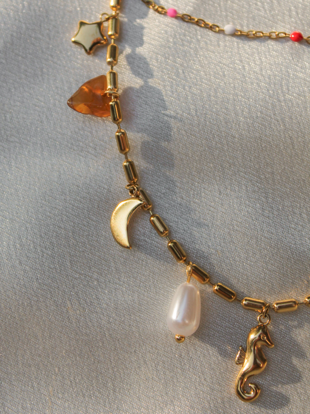 a gold charm necklace with summer charms 