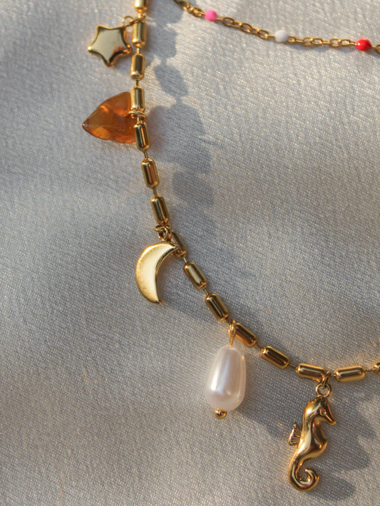 a gold charm necklace with summer charms 