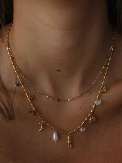 a close up of a girl wearing a double layered gold necklace with sea creature and celestial charms