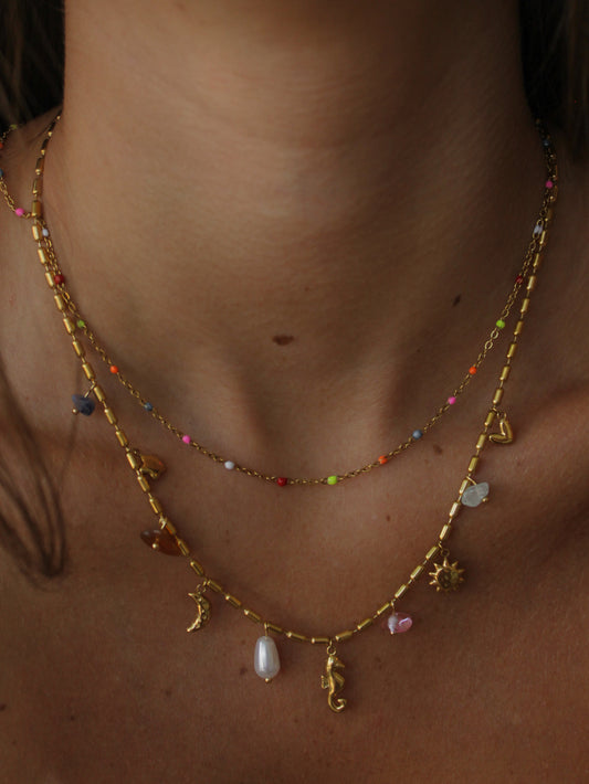 a close up of a girl wearing a double layered gold necklace with sea creature and celestial charms