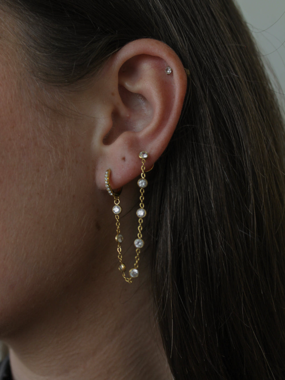 woman wearing a double piercing earring with a gold hoop and stud that connect them together
