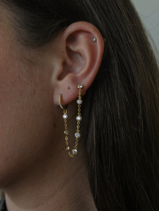 woman wearing a double piercing earring with a gold hoop and stud that connect them together