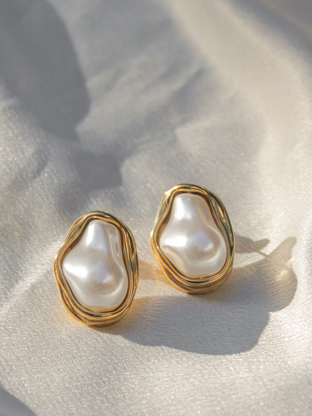 a pair of gold, organic shaped pearl stud earrings