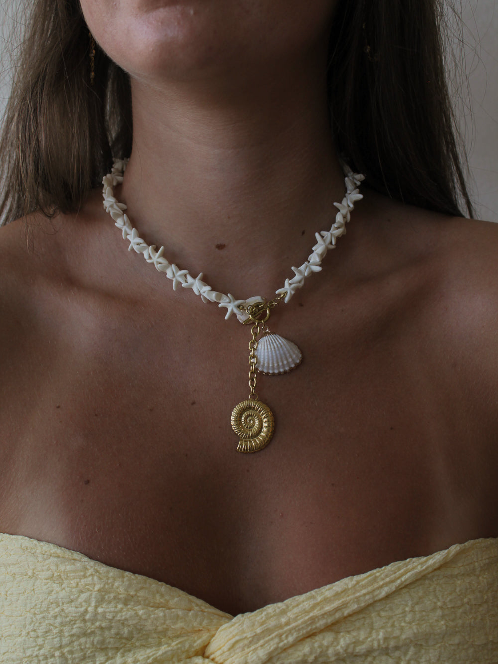 woman wearing a shell chain necklace with a cluster of shell charms