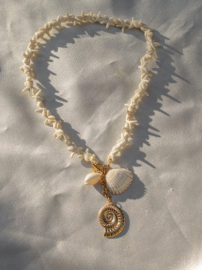 a necklace made of small star shell charms with a cluster of gold and seashell charms at the end