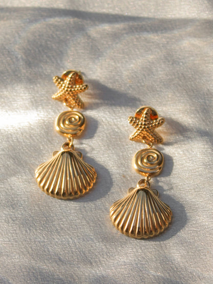 a pair of gold shell drop earrings, featuring a starfish and clam shell