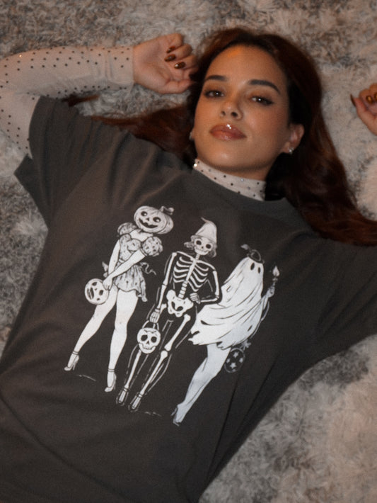 Woman wearing a dark grey tee shirt with a graphic of three ghoulish girls