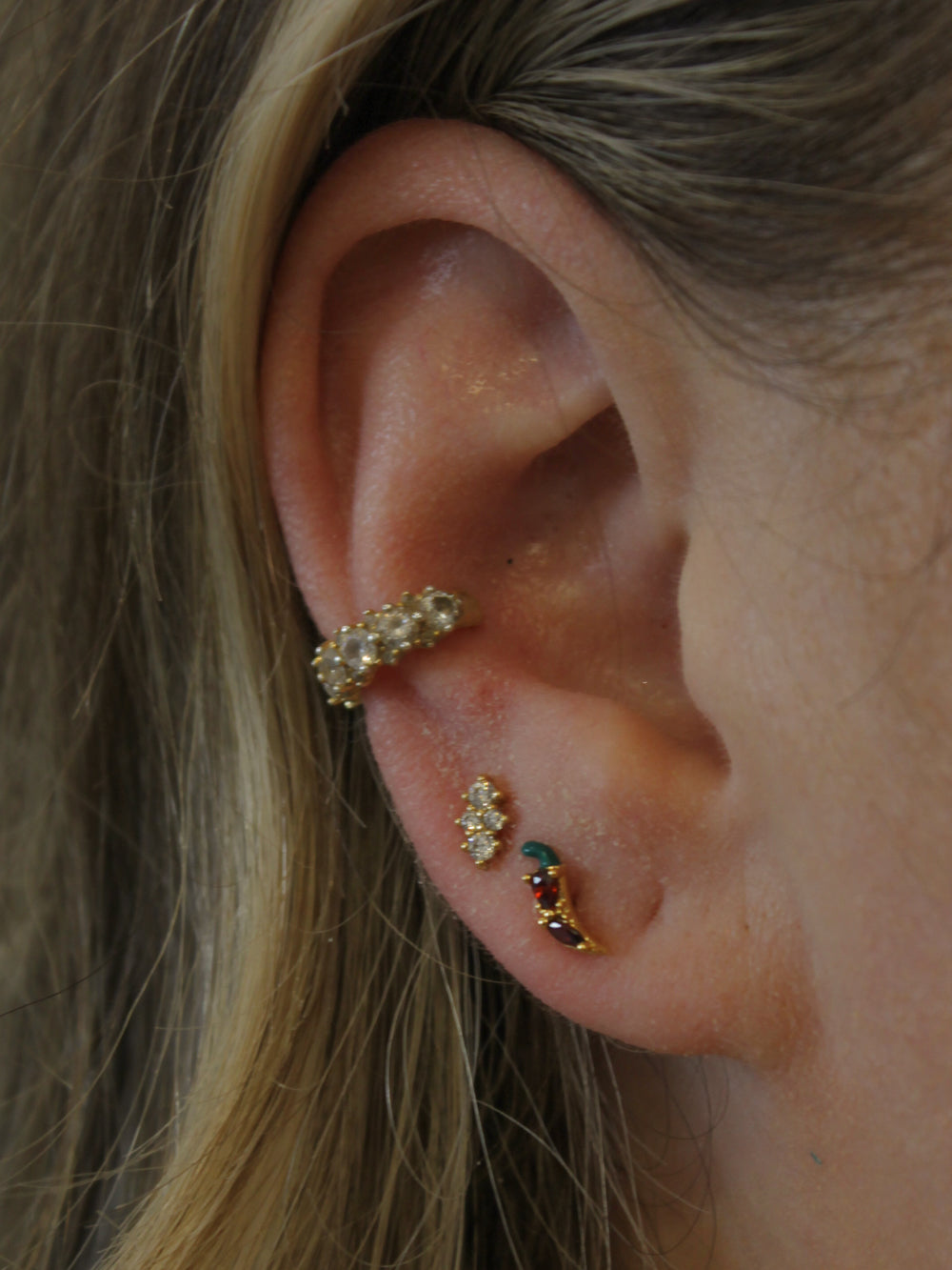 Red Hot Chili Pepper stud earring shown in the ear and stacked and styled with other gold earrings.