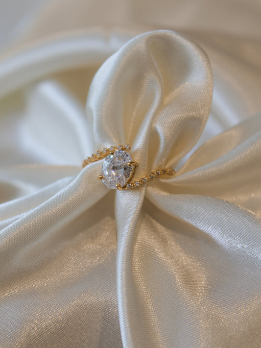 Gold solitaire ring displayed on a satin display