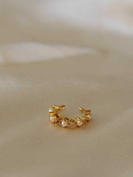 A dainty, gold ear cuff with pearl and clear stones