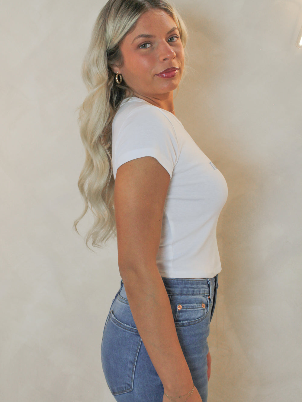 Side view of a woman wearing a white baby doll style tee.