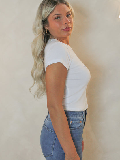 Side view of a woman wearing a white baby doll style tee.