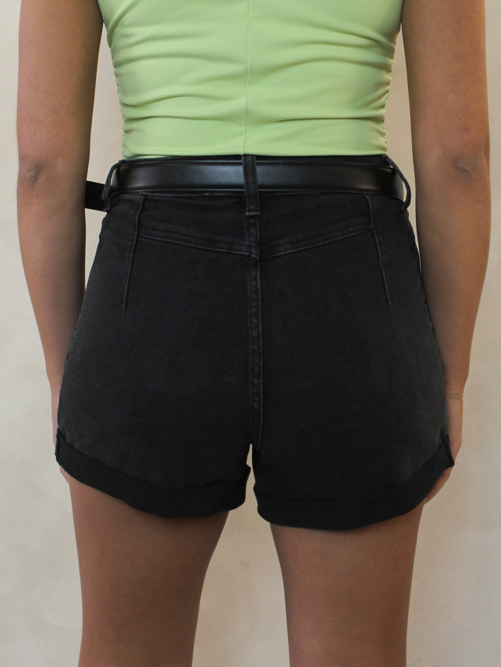 A pair of black denim shorts with cuffed hems from the back 