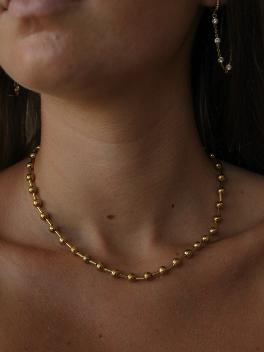 a close up of a girl wearing a gold ball chain.