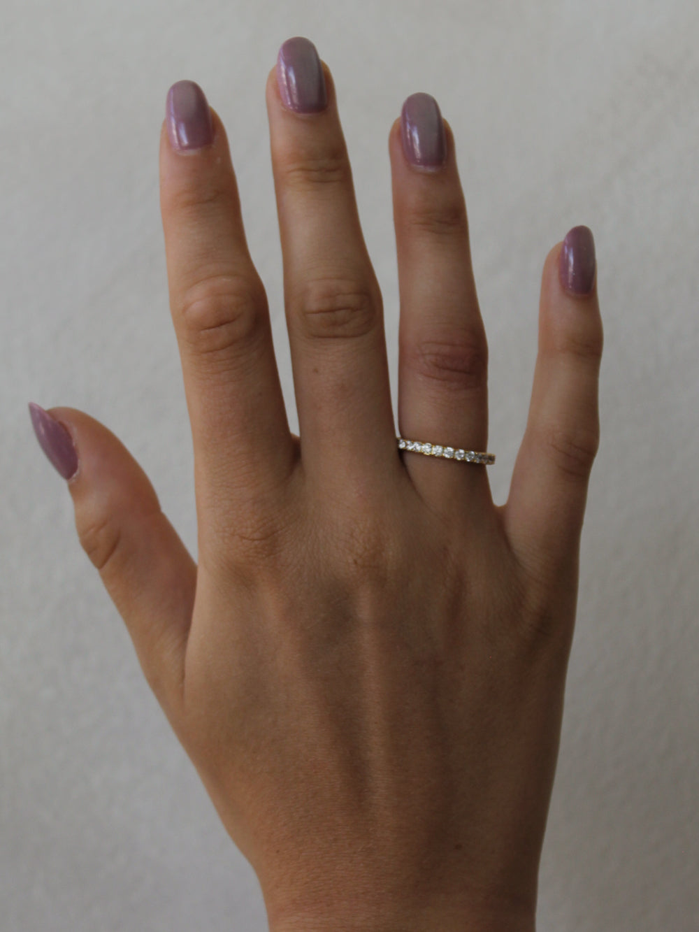 a girls hand wearing a single thin gold eternity band 