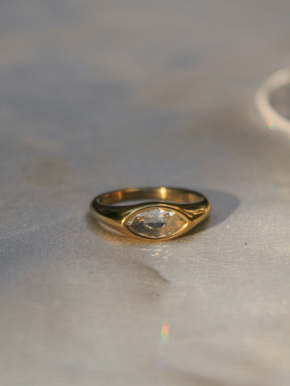 A gold signet ring with a marquise-cut clear gemstone.