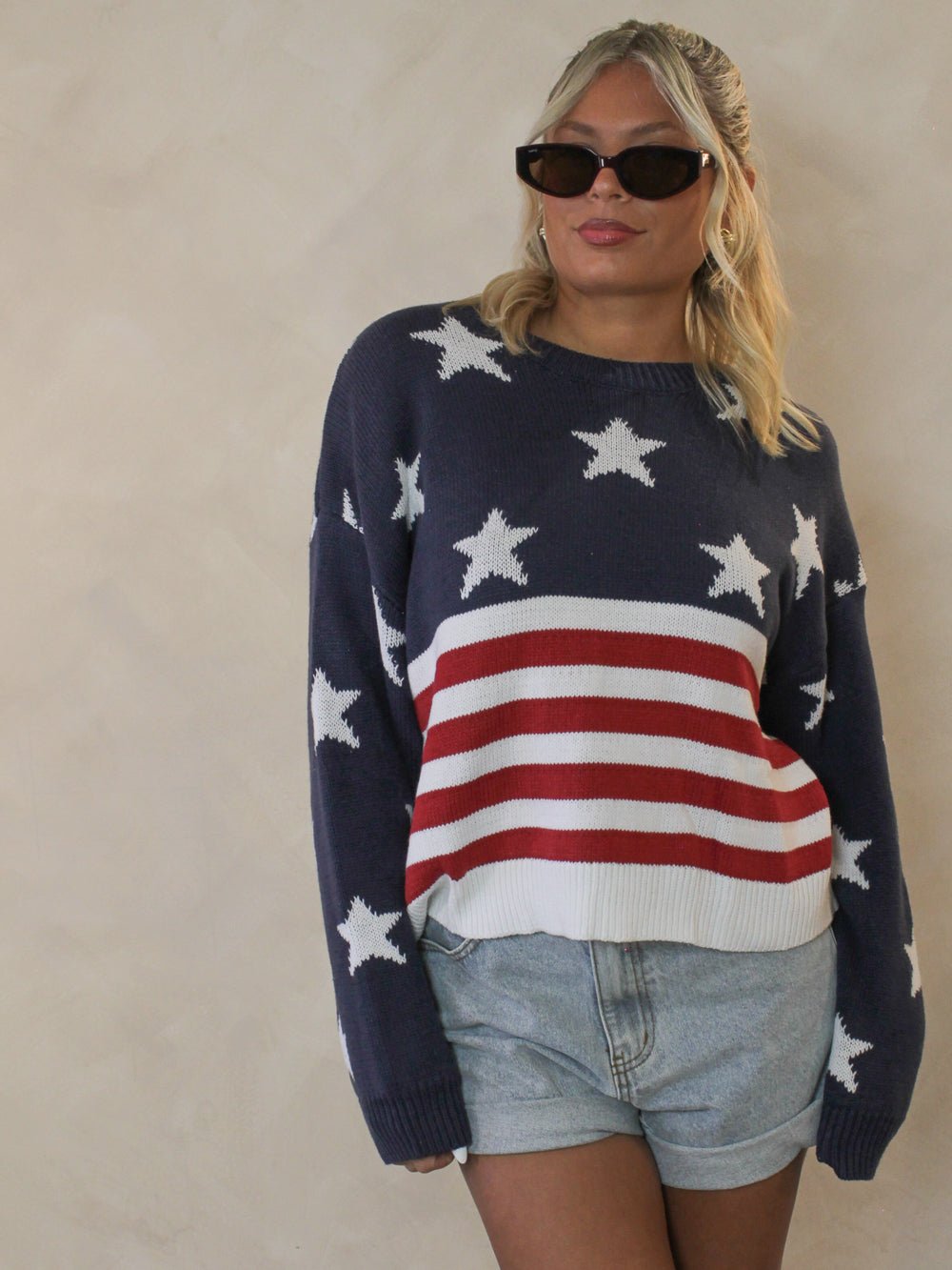 Woman wearing an american flag sweater styled with denim shorts