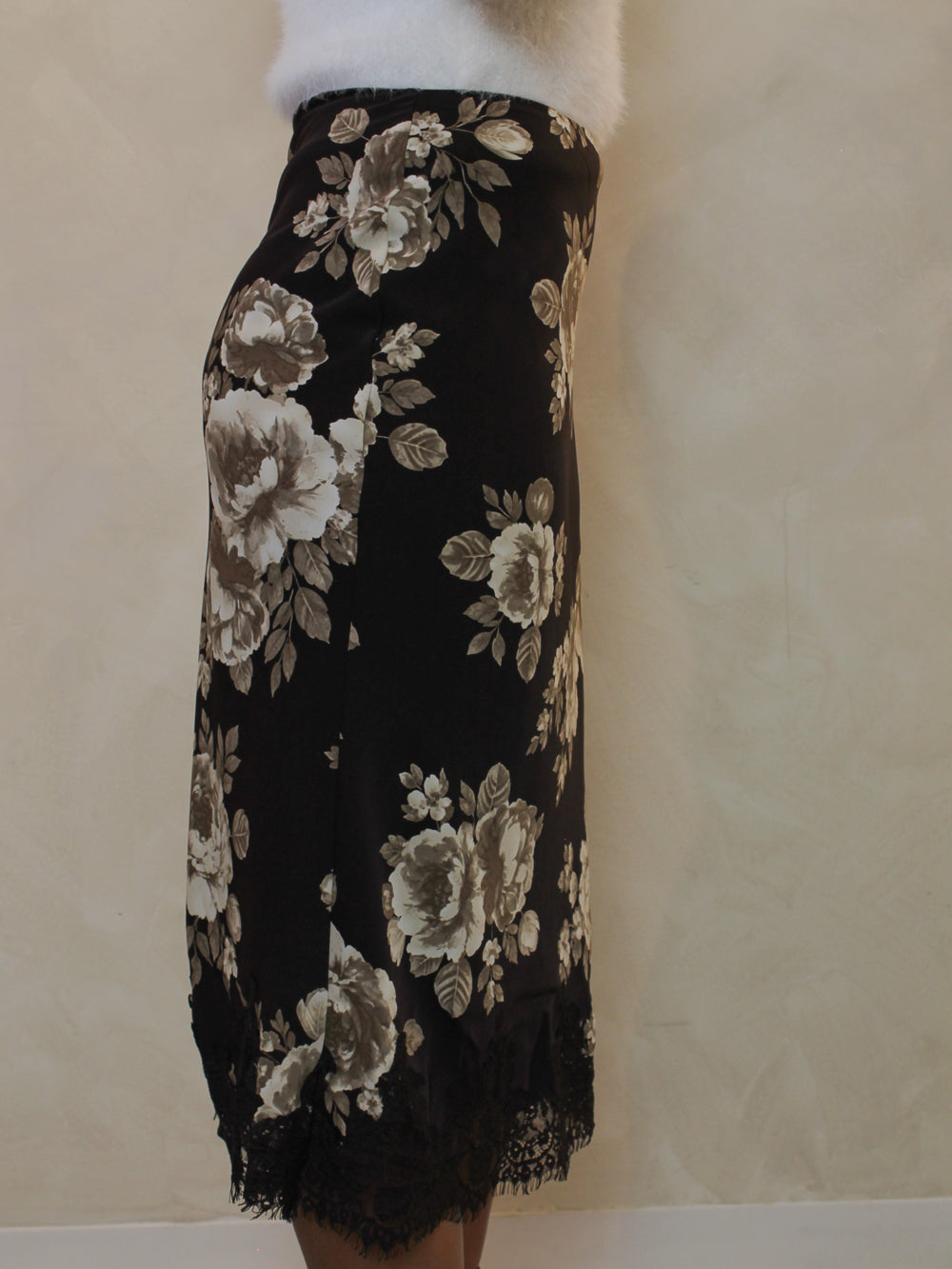 Side view of a chocolate brown floral satin midi skirt with a lace hem