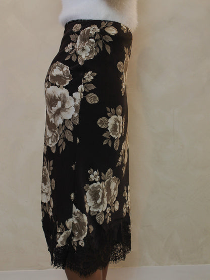 Side view of a chocolate brown floral satin midi skirt with a lace hem