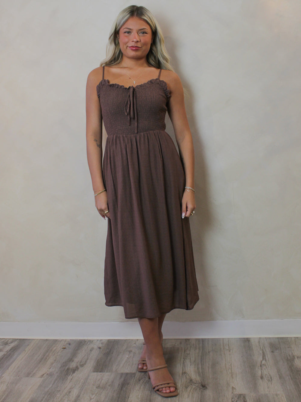 Model wearing a brown, smocked midi dress with eyelet trim 