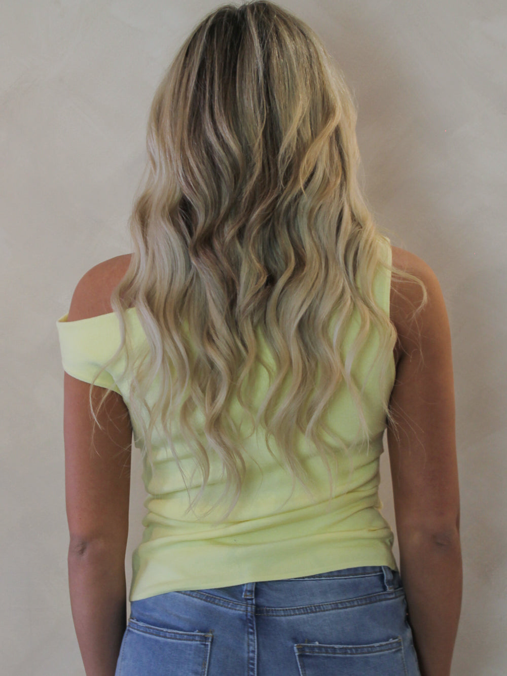 Back view of a model wearing an off the shoulder top in light yellow 