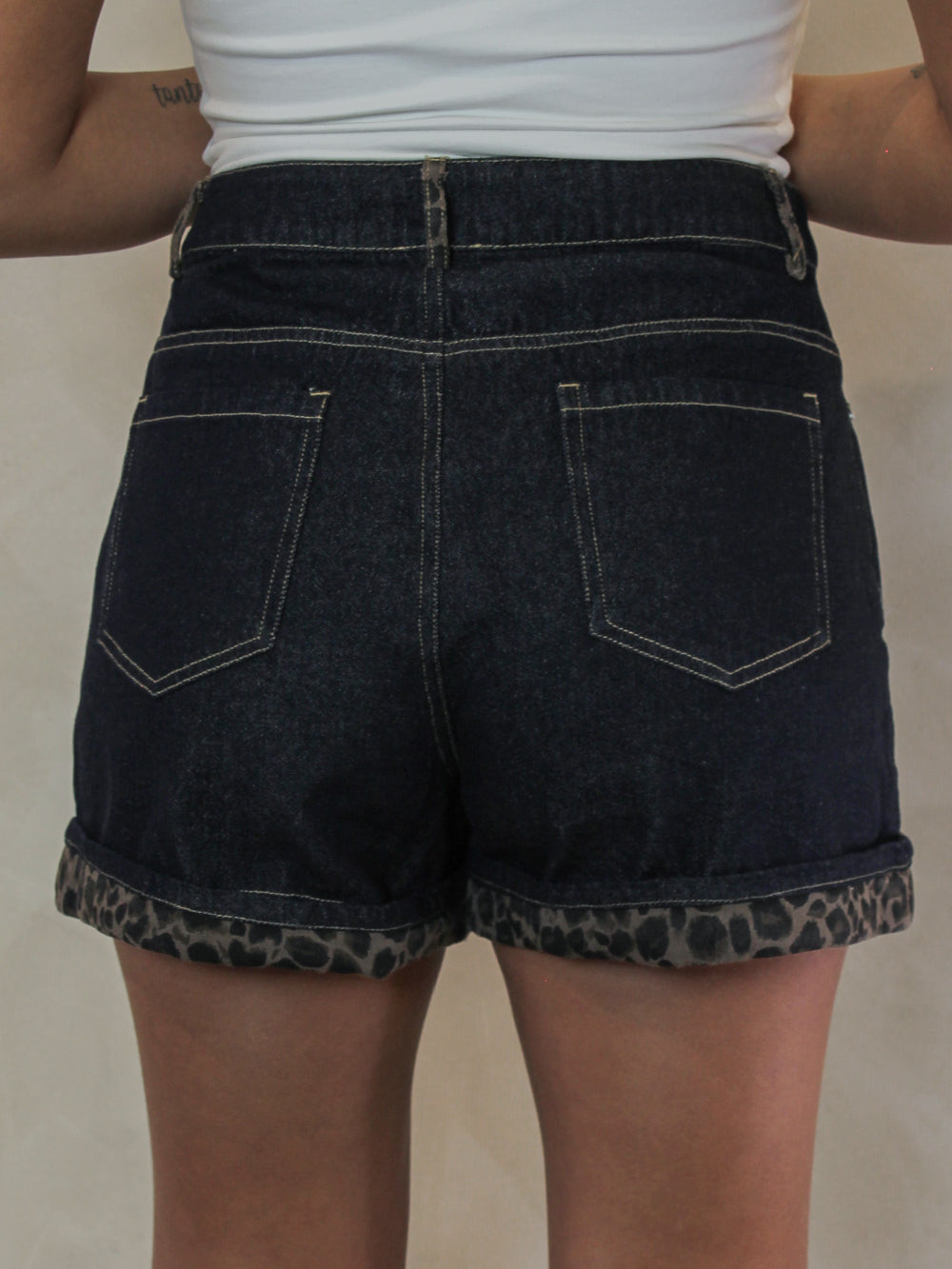 back view of  dark wash denim shorts for women with a leopard print cuffed hem
