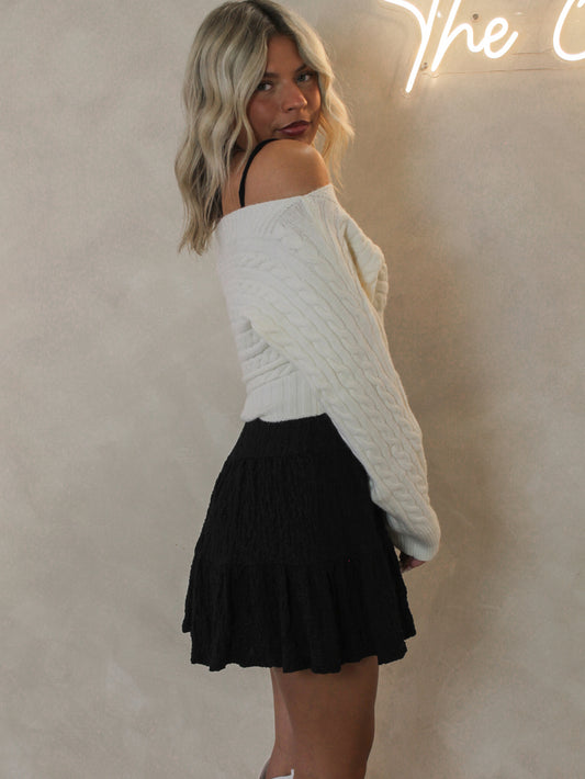 Woman wearing a white sweater and black skirt 