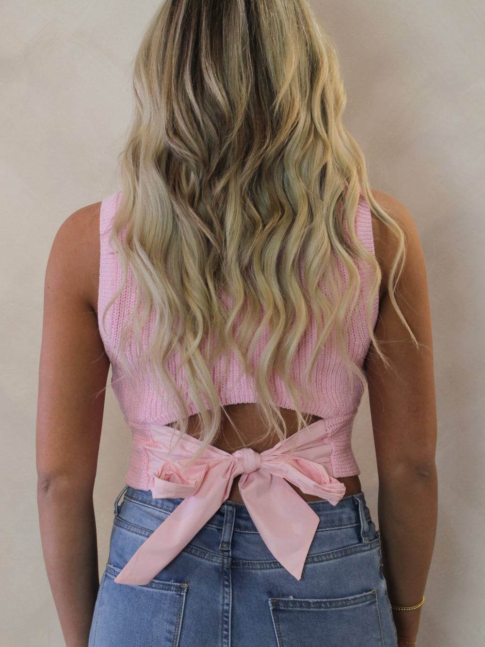 Pink sleeveless sweater with a bow tie back detail 