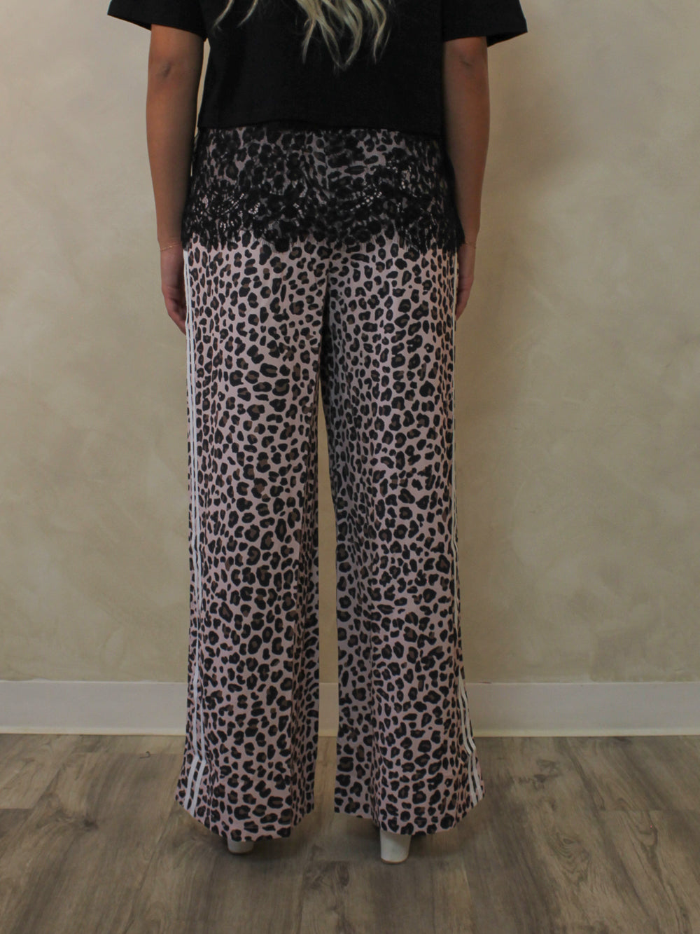 Back view of a woman model wearing a pair of leopard print pants.